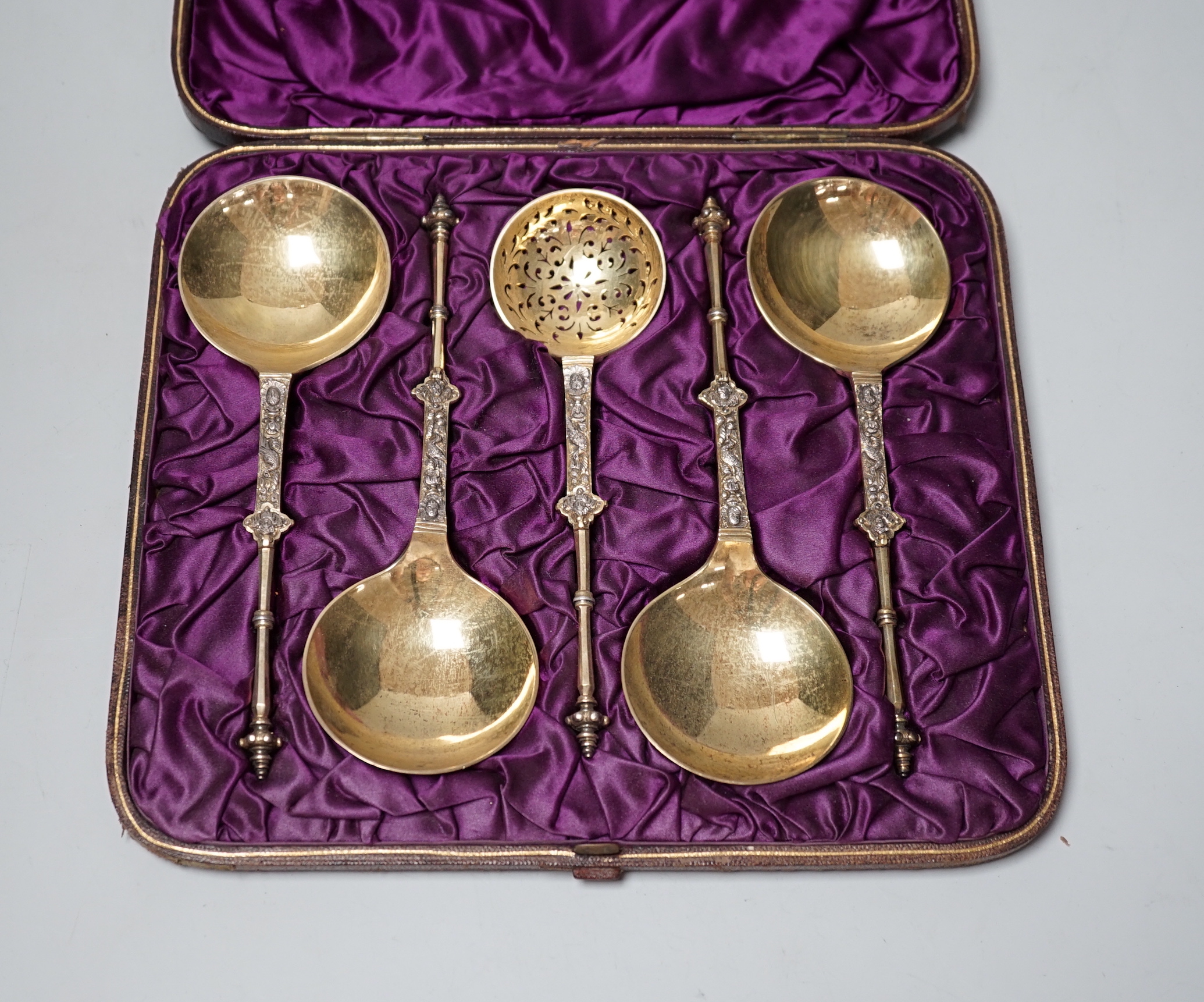 A cased late Victorian silver gilt dessert set comprising four serving spoons and one sifter spoon, Holland, Aldwinckle & Slater London, 1881, 7.7oz.